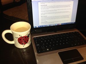 Laptop with a cup of coffee in a ladybird mug